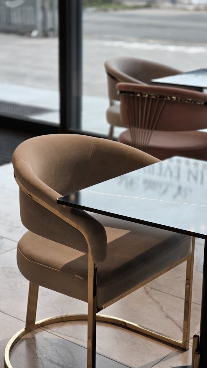 Sleek beige chair with a mirrored table in a contemporary cafe setting.